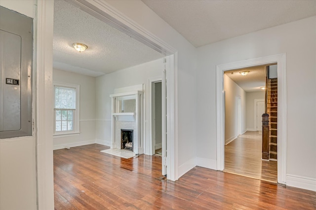 1107 Heard Ave, Augusta, GA 30904 - unfurnished living room featuring wood finished floors, electric panel, a brick fireplace, and a textured ceiling