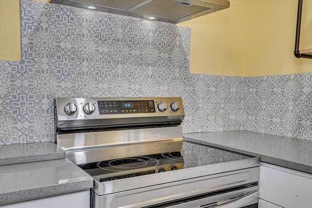 1107 Heard Ave, Augusta, GA 30904 - kitchen with stainless steel electric range oven, wall chimney range hood, decorative backsplash, and white cabinetry
