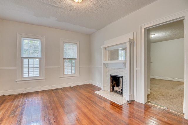 1107 Heard Ave, Augusta, GA 30904 - unfurnished living room with a textured ceiling, a fireplace, and wood-type flooring