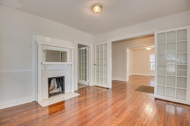 1107 Heard Ave, Augusta, GA 30904 - unfurnished living room with wood finished floors, a textured ceiling, a fireplace, and french doors