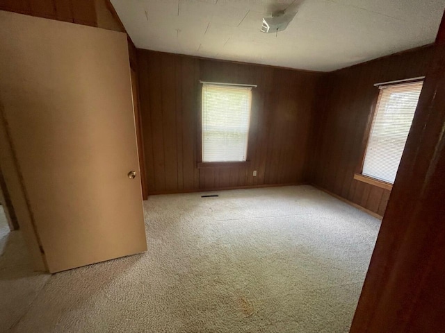 unfurnished room featuring light carpet and wood walls