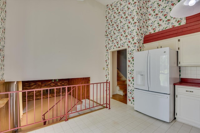904 Big Hunt Rd, Augusta, GA 30907 - kitchen featuring white refrigerator with ice dispenser, white cabinets, wallpapered walls, dark countertops, and tasteful backsplash