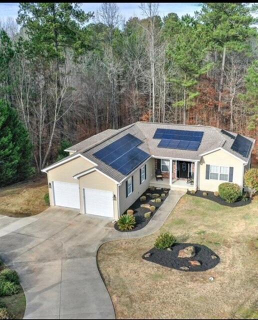 view of front of home with a front yard, solar panels, and a garage