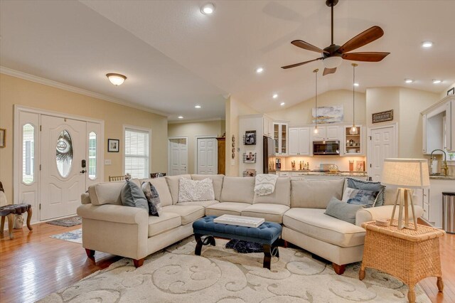 living room featuring lofted ceiling, crown molding, sink, ceiling fan, and light hardwood / wood-style floors