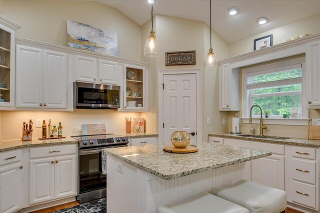 kitchen with white cabinets, sink, appliances with stainless steel finishes, and vaulted ceiling