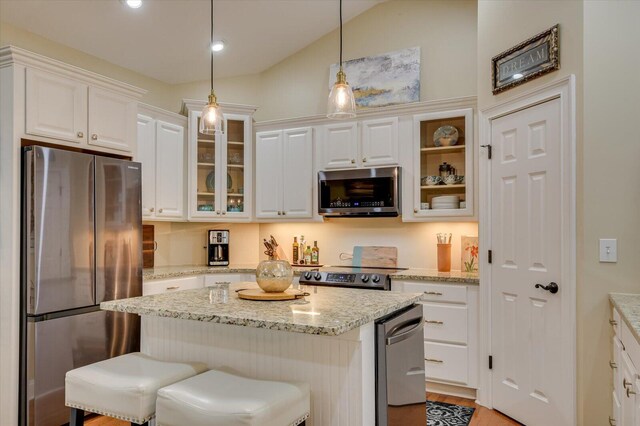 kitchen featuring white cabinetry, stainless steel appliances, hanging light fixtures, and vaulted ceiling