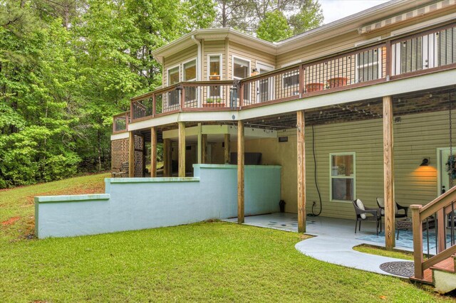 rear view of property with a wooden deck, a yard, and a patio