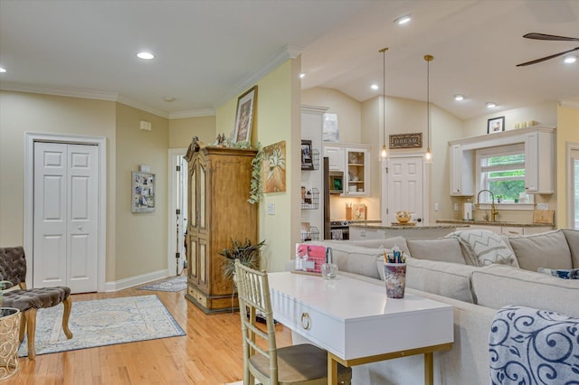 living room featuring ceiling fan, sink, light hardwood / wood-style flooring, crown molding, and vaulted ceiling