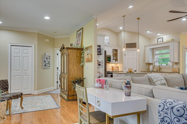 living room featuring ceiling fan, sink, light hardwood / wood-style flooring, crown molding, and vaulted ceiling