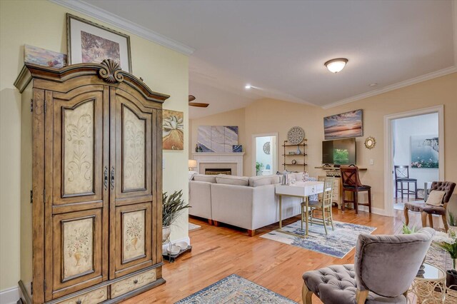 living room with light hardwood / wood-style floors, vaulted ceiling, and crown molding