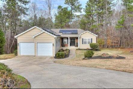 ranch-style home with a garage, a front yard, and solar panels