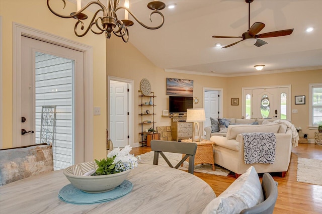 dining space featuring ornamental molding, ceiling fan with notable chandelier, light hardwood / wood-style floors, and lofted ceiling