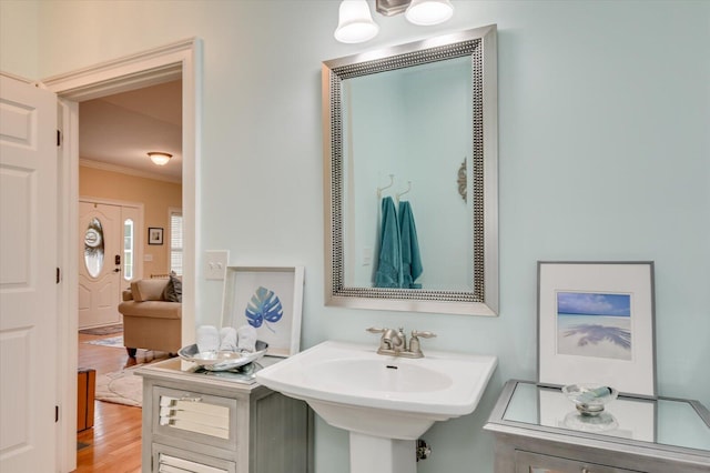 bathroom featuring hardwood / wood-style floors, crown molding, and sink