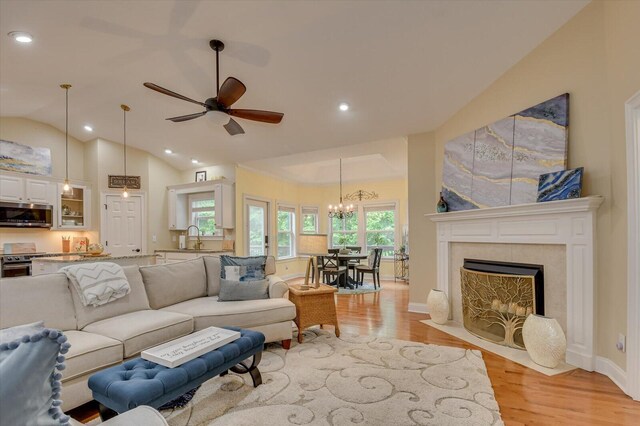 living room with light hardwood / wood-style floors, ceiling fan, lofted ceiling, and sink