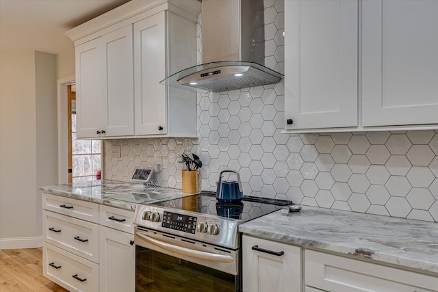 kitchen featuring stainless steel range with electric stovetop, white cabinets, wall chimney range hood, and decorative backsplash