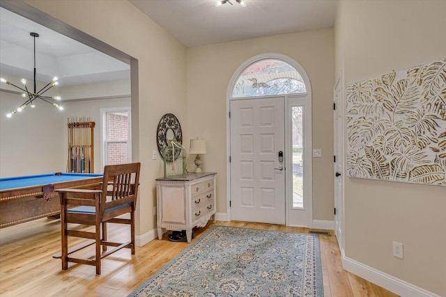 entryway with light wood-type flooring, baseboards, a chandelier, and pool table