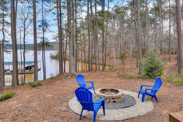 view of yard with an outdoor fire pit, a water view, and a floating dock