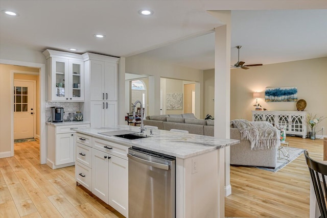 kitchen featuring ceiling fan, a sink, stainless steel dishwasher, light wood finished floors, and tasteful backsplash