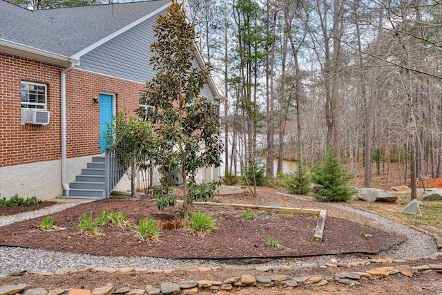 exterior space with cooling unit, roof with shingles, and brick siding