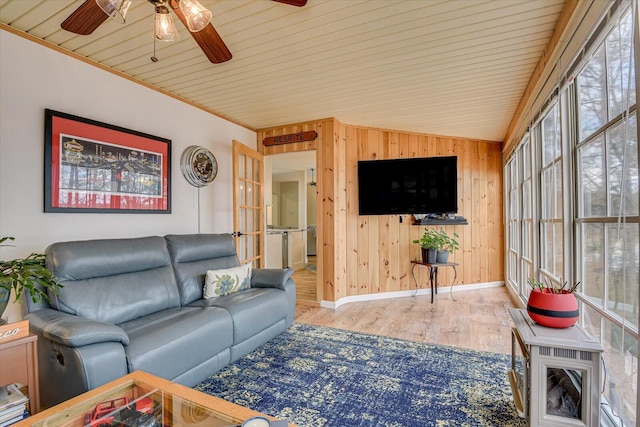 living area featuring wood walls, plenty of natural light, vaulted ceiling, and wood finished floors