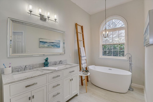 bathroom with double vanity, a soaking tub, a sink, and wood finished floors