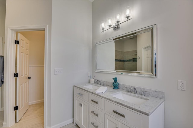 bathroom with double vanity, wood finished floors, a sink, and baseboards