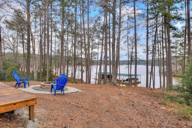 view of yard featuring a boat dock, a water view, and a fire pit