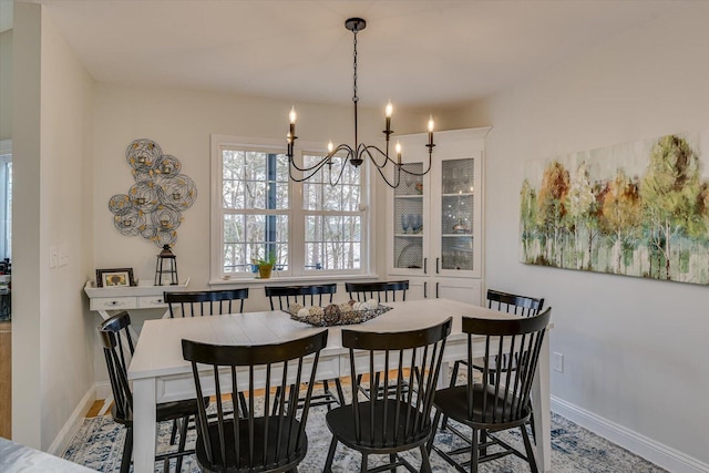 dining space with baseboards and a notable chandelier