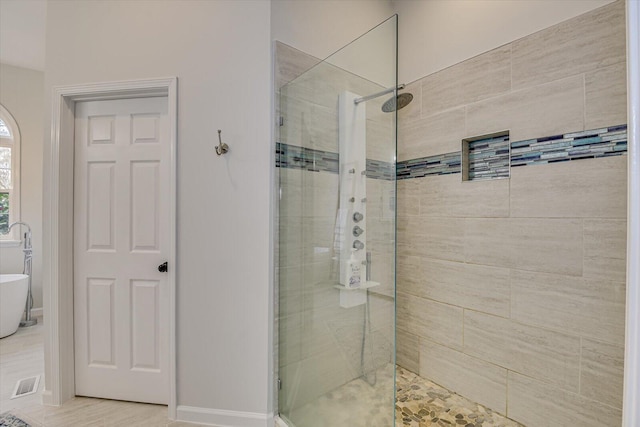 full bathroom with a stall shower, a freestanding tub, and visible vents