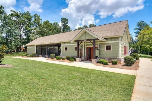 view of front of property featuring board and batten siding, a shingled roof, and a front yard