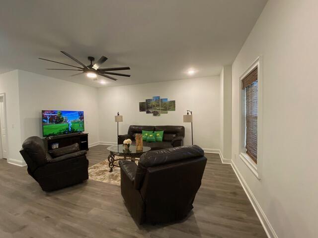 living room with a ceiling fan, dark wood-style flooring, and baseboards