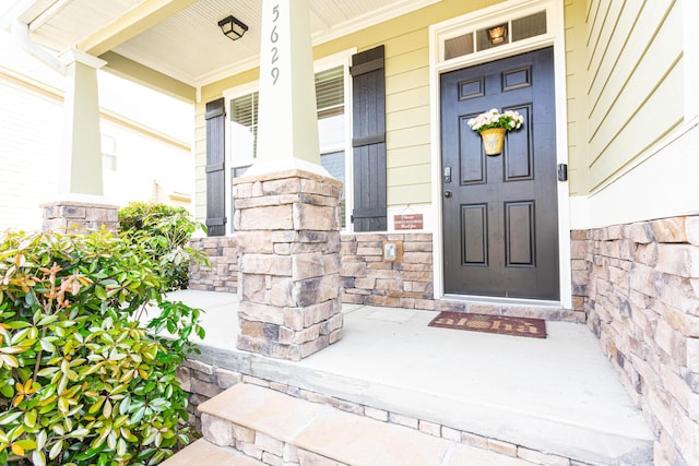 doorway to property featuring covered porch and stone siding