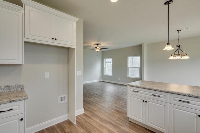 kitchen featuring ceiling fan with notable chandelier, white cabinets, light wood-type flooring, and pendant lighting