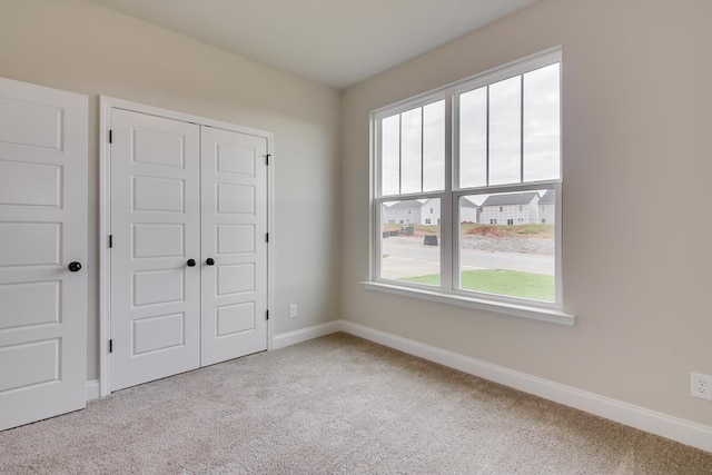 unfurnished bedroom with light colored carpet, a closet, and multiple windows