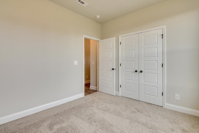 unfurnished bedroom featuring a closet and light colored carpet