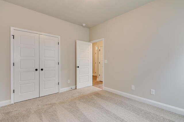 unfurnished bedroom with light colored carpet and a closet