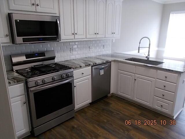967 Windmill Pkwy, Evans, GA 30809 - kitchen with stainless steel appliances, white cabinetry, dark wood finished floors, tasteful backsplash, and light stone countertops