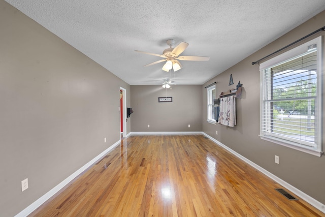 unfurnished room featuring a textured ceiling, light wood-type flooring, a ceiling fan, and baseboards