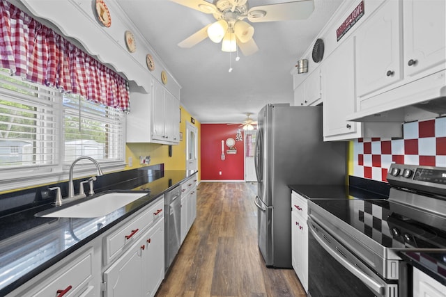 kitchen featuring appliances with stainless steel finishes, a ceiling fan, under cabinet range hood, a sink, and dark countertops