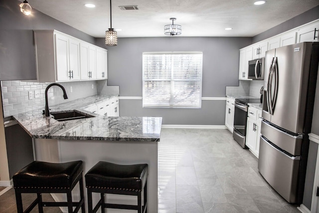 kitchen featuring light stone countertops, decorative backsplash, stainless steel appliances, sink, and decorative light fixtures