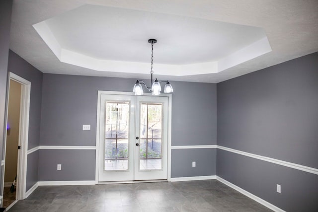 interior space with a tray ceiling, french doors, and a chandelier