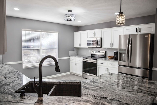 kitchen with decorative backsplash, appliances with stainless steel finishes, light stone counters, decorative light fixtures, and white cabinets