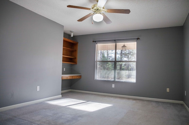 carpeted spare room featuring a textured ceiling and ceiling fan