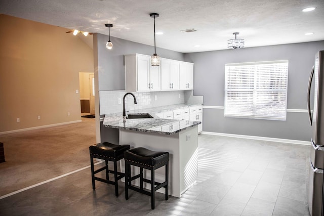 kitchen with light stone countertops, a kitchen breakfast bar, tasteful backsplash, decorative light fixtures, and white cabinets