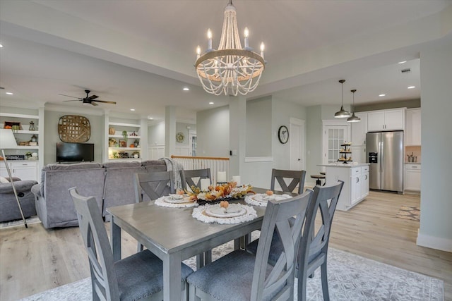 dining area with ceiling fan with notable chandelier, light hardwood / wood-style flooring, and built in features