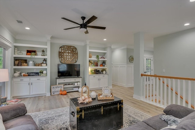 living room with built in shelves, a healthy amount of sunlight, and light wood-type flooring