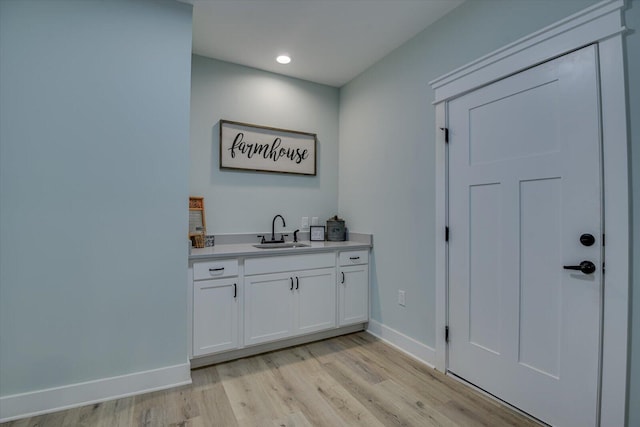 bar featuring white cabinetry, sink, and light wood-type flooring