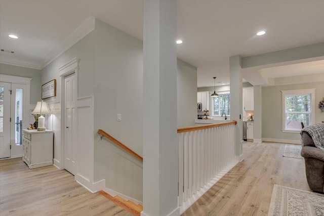 hall with light hardwood / wood-style floors and crown molding