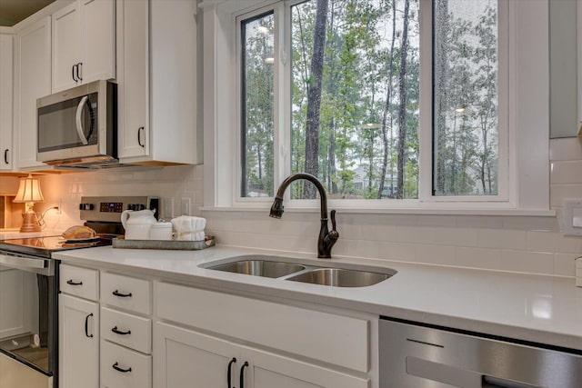 kitchen with white cabinets, decorative backsplash, sink, and appliances with stainless steel finishes