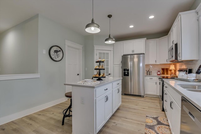 kitchen with white cabinets, a center island, light hardwood / wood-style floors, and stainless steel appliances